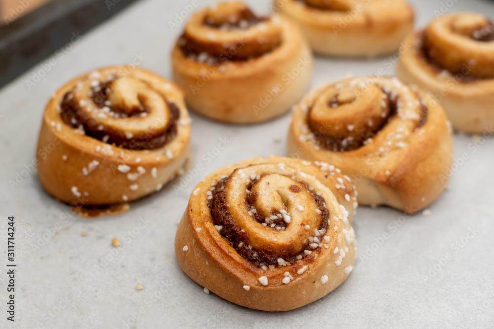 Freshly baked cinnamon buns rolls on a tray lined with baking parchment paper