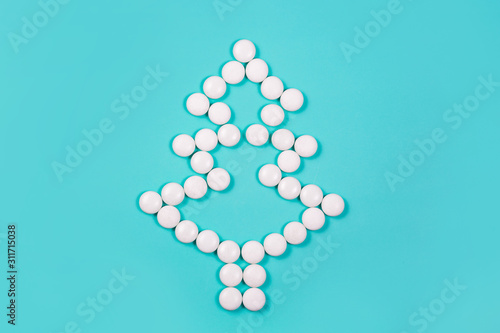 Elegant Christmas tree of white pills on blue background. Christmas and New year concept. Holiday for health care, medical and pharmacy chain. Creative minimalist medicines. Copy space