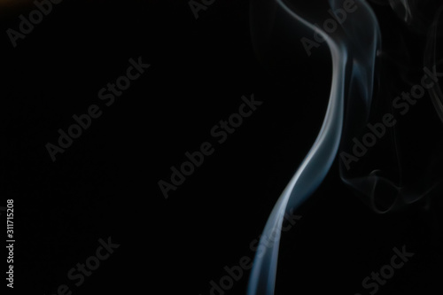 Abstract smoke background with copy space on black background. Blue-white smoke rising from the incense stick