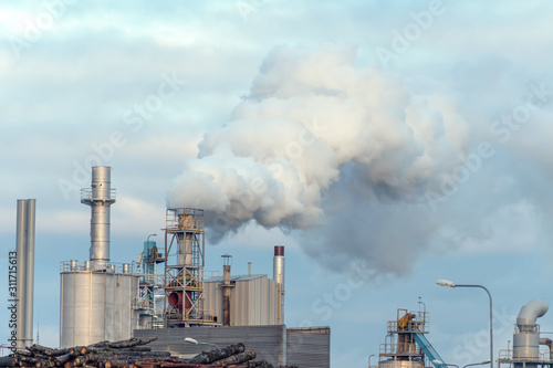 Woodworking plant  thick smoke from the pipes against the gray-blue sky. Environmental pollution.