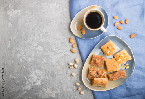 traditional arabic sweets and a cup of coffee on a gray concrete background. top view, copy space.