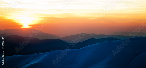 Panoramic sunset view of winter mountain hills covered with snow