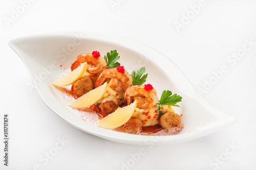 Tiger prawns with red caviar in a restaurant close-up. Fried shrimp on mashed potatoes on a white plate and copy space.