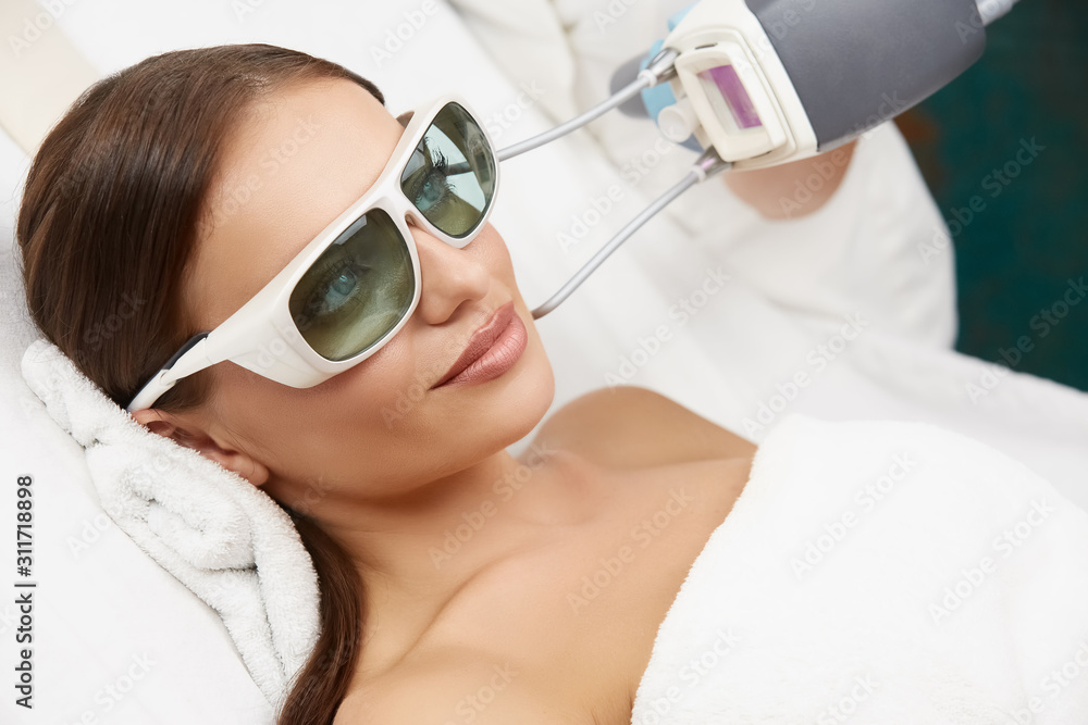 close-up of attractive woman receiving laser rejuvenation in beauty salon by beautician