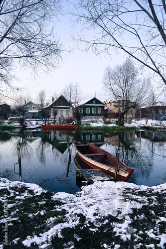 Wooden fishing boat on the bank of the river on the background of houses