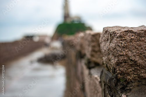 Stone of the wall close-up. Old bridge with ancient building on the sea side  cloudy sky  rain