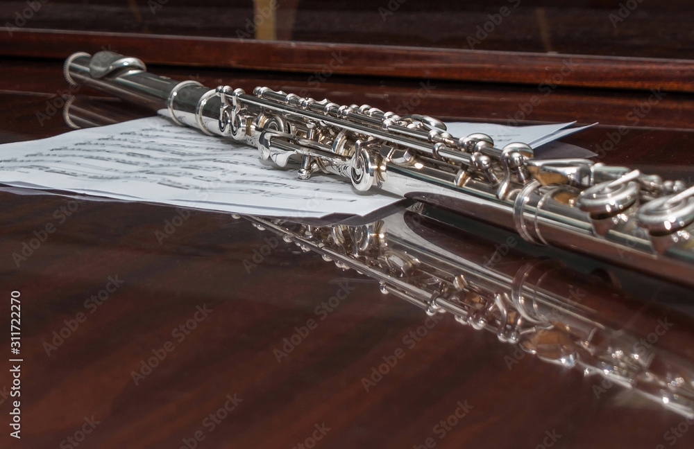 Obraz premium Flute lying on a sheet with notes, selective focus.