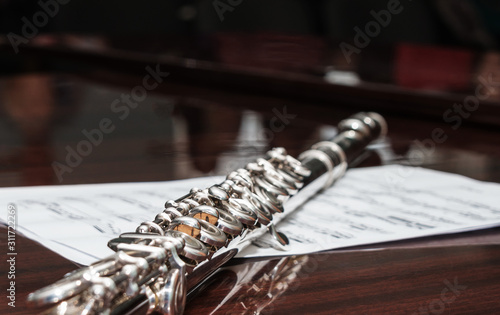 Flute lying on a sheet with notes, selective focus.