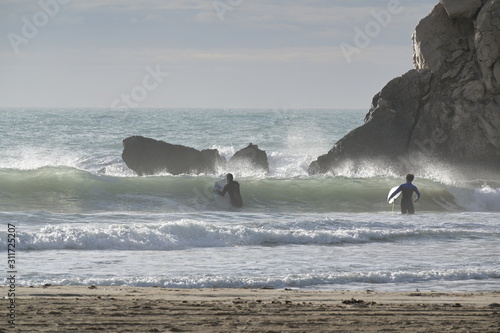 Two surfer in the surf at the foggy coast of Benidorm-Spain.