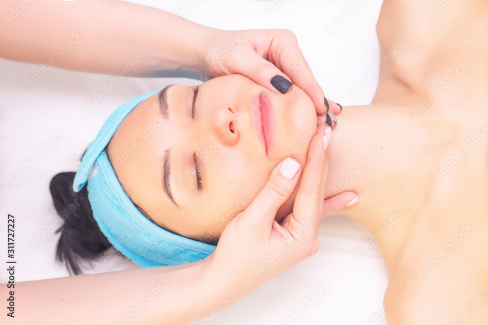 Young woman enjoying massage in spa salon. Face massage. Closeup of young woman getting spa massage treatment at beauty spa salon.Spa skin and body care. Facial beauty treatment.Cosmetology.