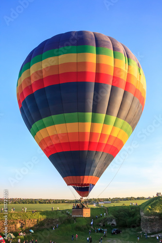 Big colorful hot air balloon flying in sunny blue sky