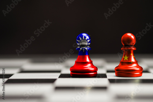 China and Taiwan flag print screen on pawn chess with black background. Now both countries have economic and patriotic conflict.