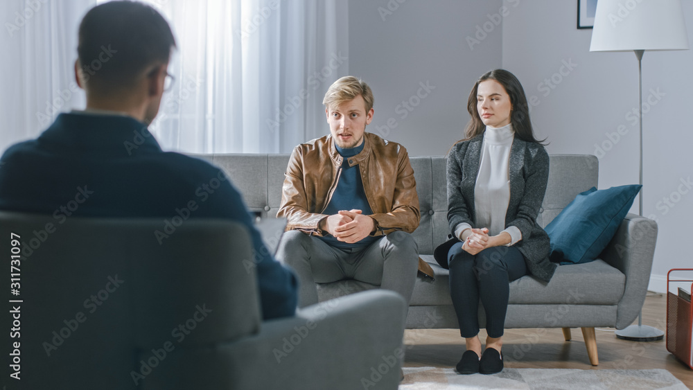 Young Couple on a Counseling Session with Psychotherapist. Back View of Therapist Taking Notes: Young People Sitting on the Analyst Couch, Discussing Psychological Issues and Relationship Problems