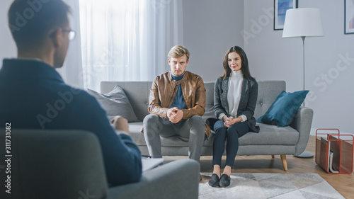 Young Couple on a Counseling Session with Psychotherapist. Back View of Therapist: Young People Sitting on the Analyst Couch, Discussing Psychological Trauma, Relationship Problems, and Suffering © Gorodenkoff