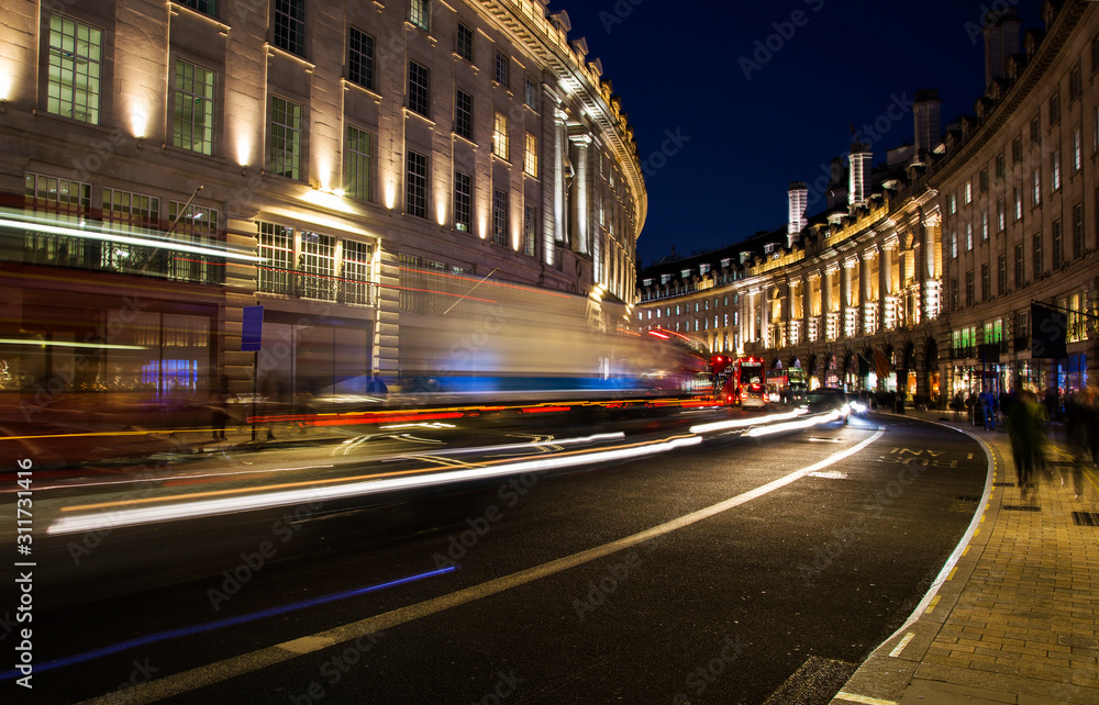 night scene of London city United Kingdom with the moving red buses and cars - long exposure photography