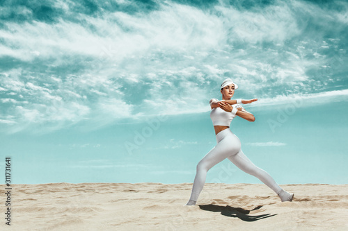 Sporty and fit young woman athlete relaxed after training at the desert. Cloudy day on coast. The concept of a healthy lifestyle and sport. Woman in white sportswear.