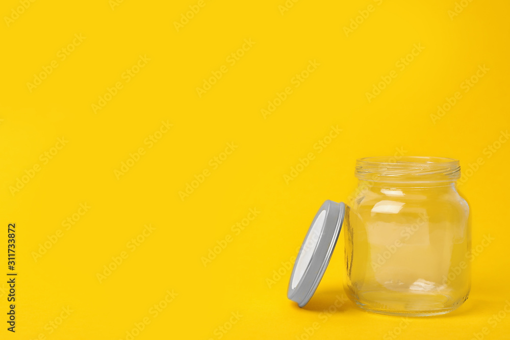 Open empty glass jar on yellow background, space for text
