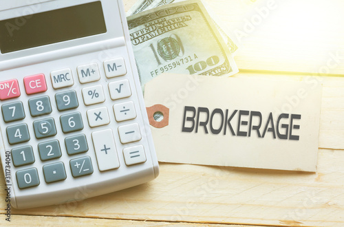 BROKERAGE Words on tag with dollar note and calculator on wood backgroud,Finance Concept