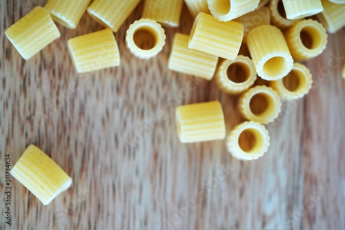 Close up view on traditional Italian pasta tubes on wooden background photo