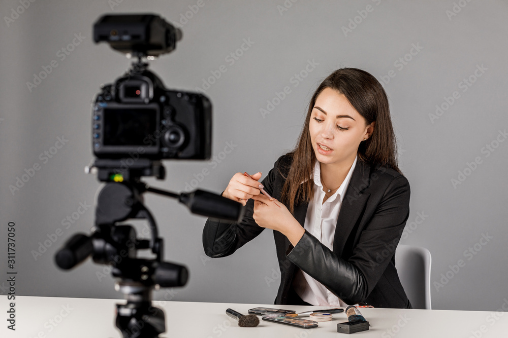 Young blogger in dark suite on grey background. Young blogger in dark suite on grey background.