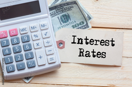 Interest Rate Words on tag with dollar note and calculator on wood backgroud,Finance Concept photo