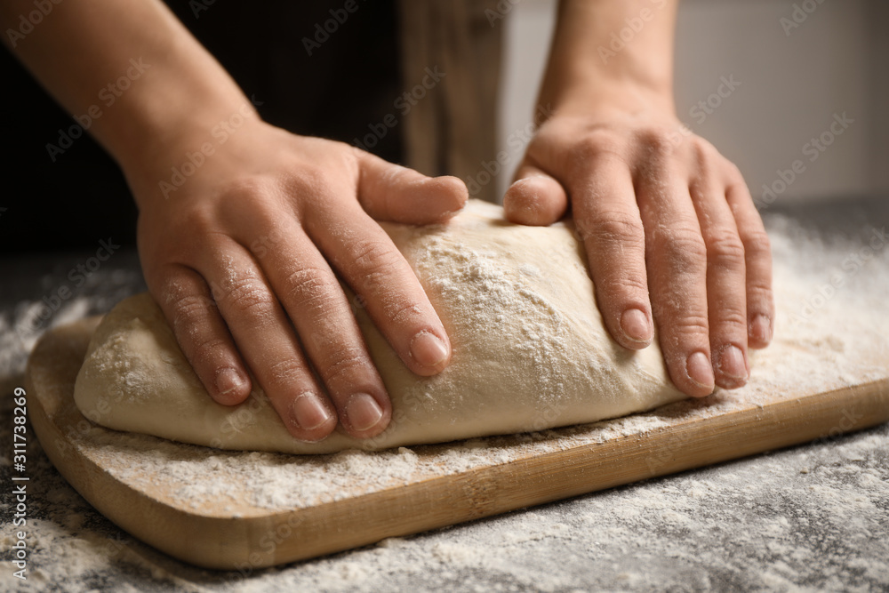Woman beating dough at table, closeup. Making pasta