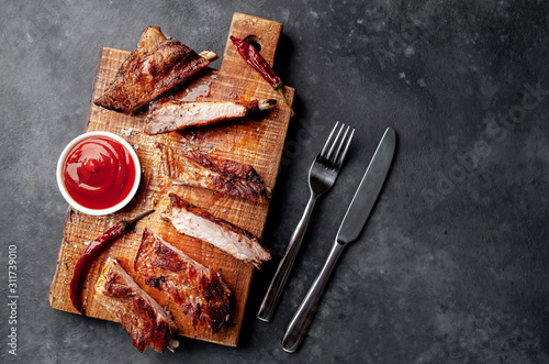 grilled pork ribs on a cutting board with spices on a stone background with copy space for your text