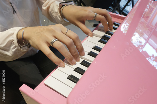 Close up the hands of a young woman playing pink tiny piano  with Selective focus