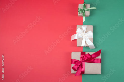 Beautiful packaging of presents with satin ribbons, craft paper on red and green background. © Анна Авдохина