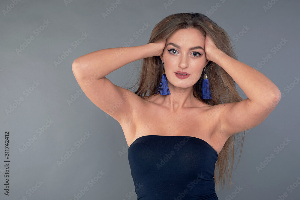 Woman with beauty long brown hair, posing at studio. long earrings classic blue Woman with beauty long brown hair, posing at studio. long earrings classic blue