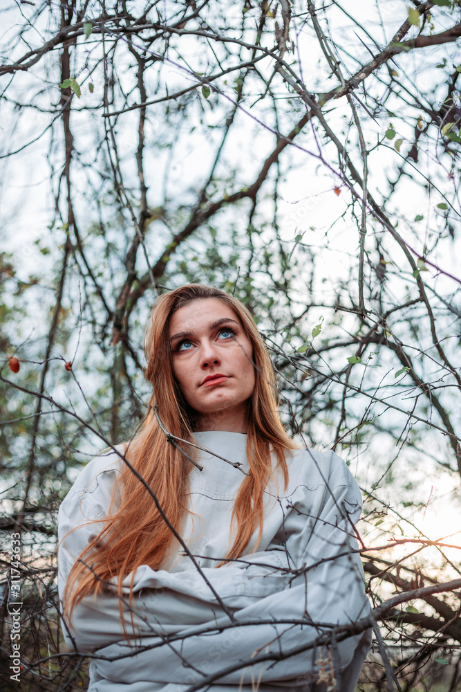 Girl in straitjacket, outside in the woods, branches surrounding her. Girl in straitjacket, outside in the woods, branches surrounding her.