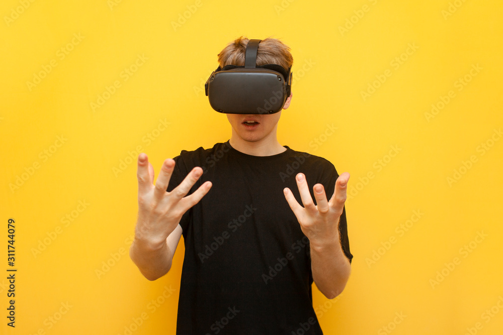 surprised guy with VR glasses touches virtual space on a yellow background, using modern virtual reality gadgets surprised guy with VR glasses touches virtual space on a yellow background, using modern virtual reality gadgets