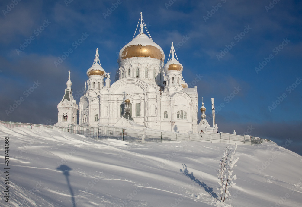 Belogorsky monastery in the Perm region on a frosty day, surrounded by snowy trees.