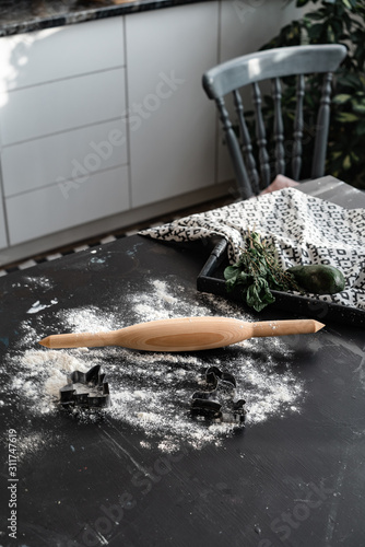 A wooden rolling pin lies on a table among flour