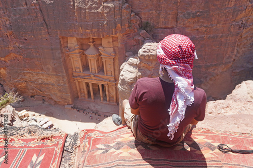 Jordan may 26 , 2019 man traveler sitting on carpet viewpoint in Petra ancient city looking at the Treasury or Al-khazneh, travel destination and one of seven wonders. UNESCO World Heritage site