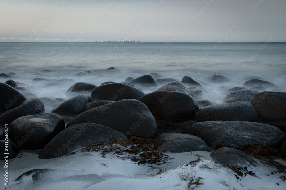 Obraz premium Selective focus completely black and round rocks because of being severely affected by ocean waves mysterious evening atmosphere. The famous tourist attraction. Eggum, Lofoten Islands, Norway