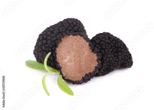 Black truffles isolated on a white background. Fresh sliced truffle with rosemary branch. Delicacy exclusive truffle mushroom. Piquant and fragrant French delicacy. Clipping path.