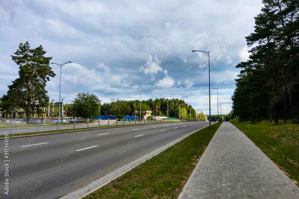 View of a wide empty road with trees on the side of the road.
