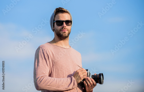 Photojournalist concept. Travel blogger. Professional photographer. Hipster reporter taking photo. Guy photographer outdoors sky background. Handsome photographer guy retro camera. Manual settings