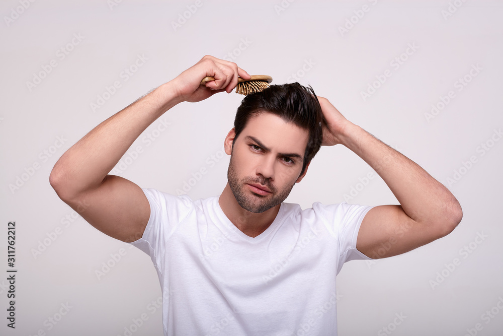 A young handsome guy combs a wooden comb. A young handsome guy combs a wooden comb.