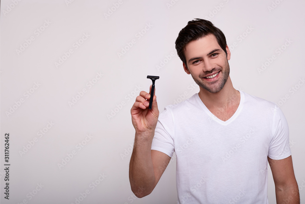 Beautiful sexy macho in a white T-shirt with a razor in his hand. Beautiful sexy macho in a white T-shirt with a razor in his hand.