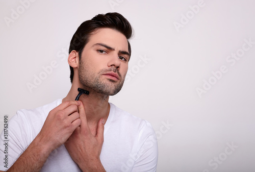 Charming serious man shaves on a white background.