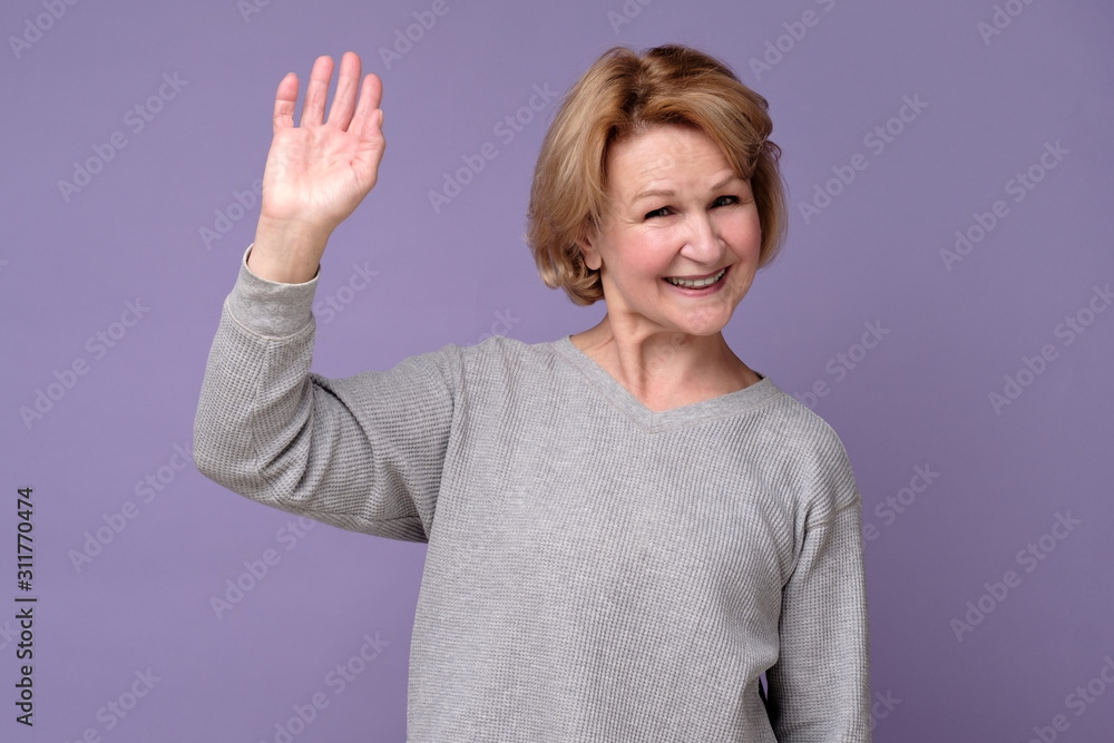 Hello concept. Happy old woman with a smile on her face fallen hand in greeting. Welcoming guests. Hello concept. Happy old woman with a smile on her face fallen hand in greeting. Welcoming guests.