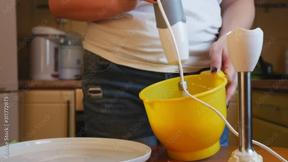 A woman stirs the mixture for cooking pancake in a plastic container blender A woman stirs the mixture for cooking pancake in a plastic container blender