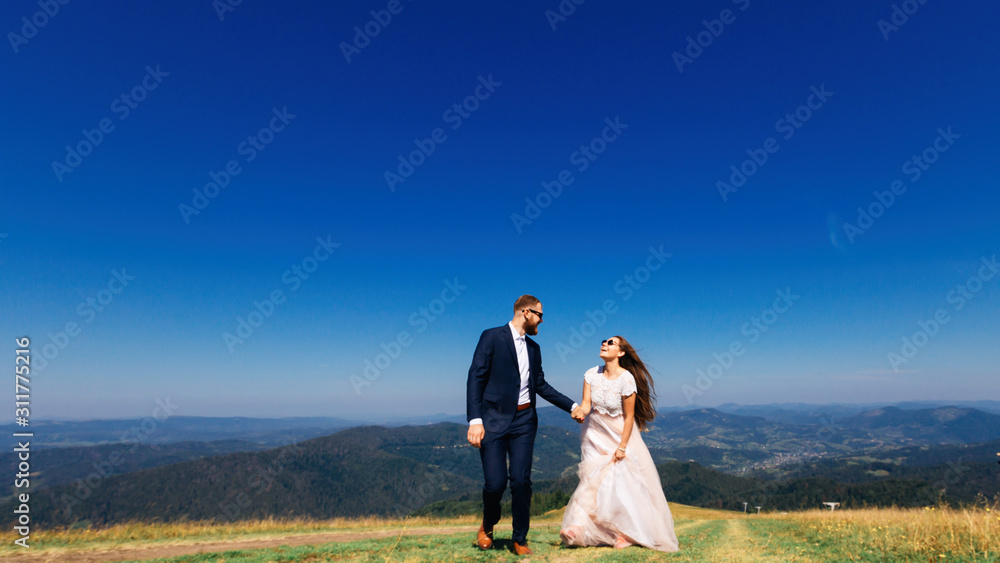 Newlyweds enjoy each other and walk on the top of the mountain w Newlyweds enjoy each other and walk on the top of the mountain w