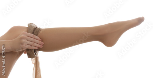 Young woman putting on tights against white background, closeup