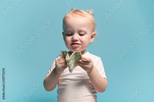 little girl is looking at the dollar that she is holding in her hands. photo