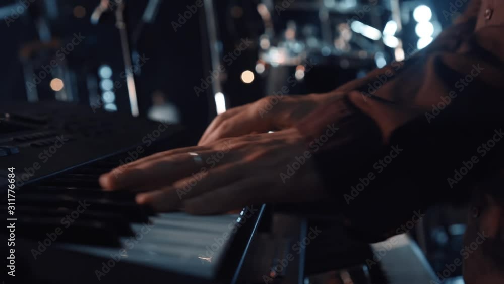 Hands of male musician playing at synthesizer. Mens arms plays solo of music or new melody. Close up fingers of pianist at the piano keys. Hands of male musician playing at synthesizer. Mens arms plays solo of music or new melody. Close up fingers of pianist at the piano keys.