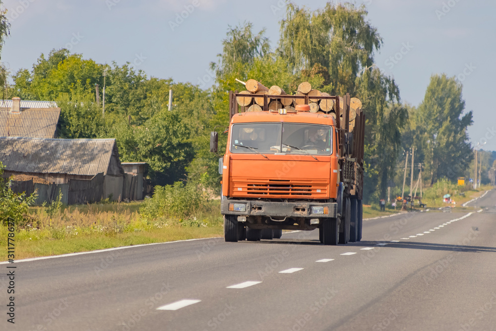 Timber truck with a forest rides on the highway with cargo