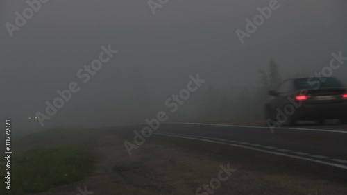 Extremal driving on the country road. Cars moving into and out of the thick fog with front, rear, fog lights and stop signal on